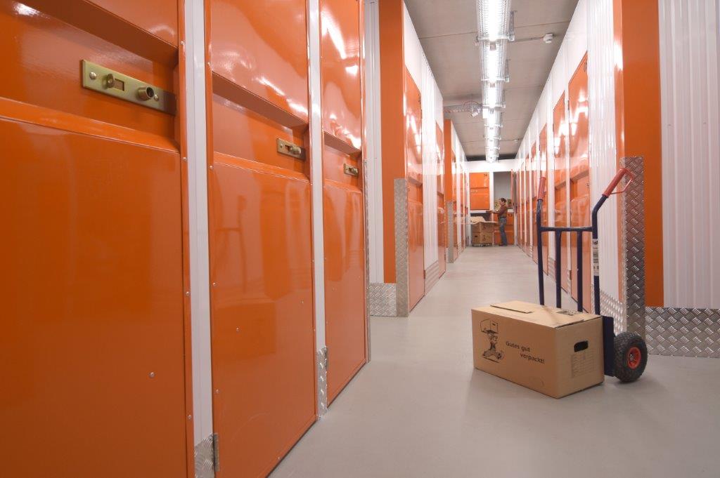 KW-Box Bremerhaven – Interior hallway with orange storage units and hand truck